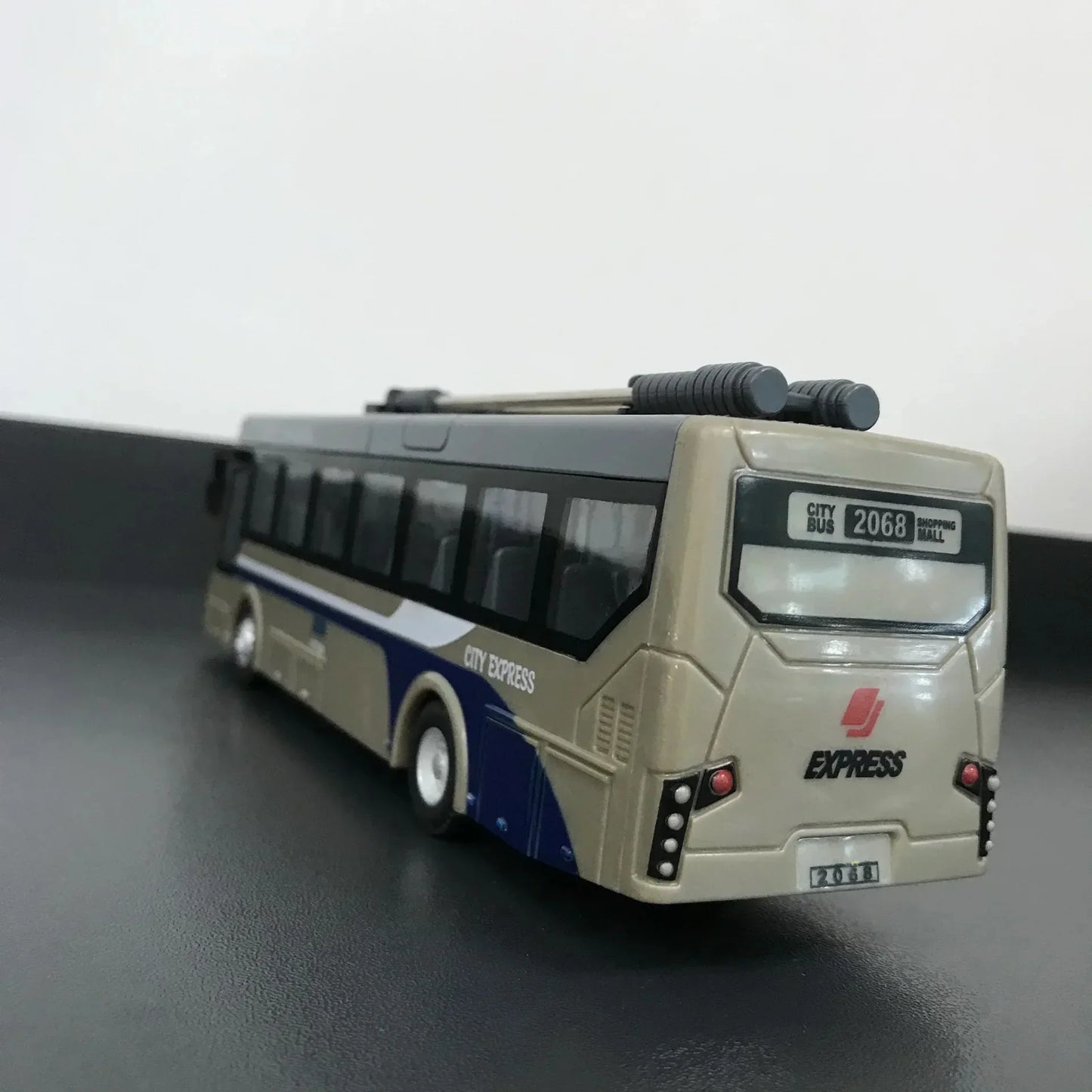 Beige and blue City Express toy bus model on black surface, rear view with route 2068 sign