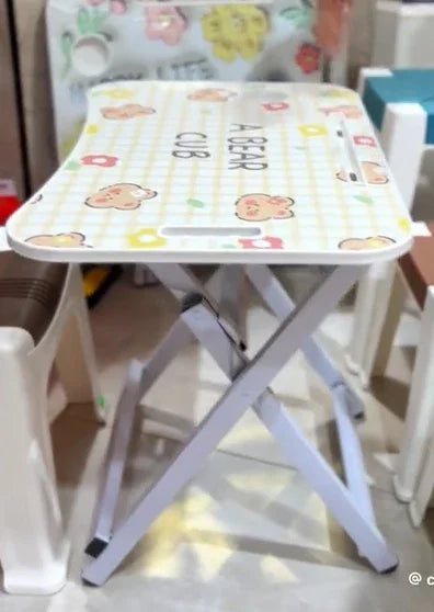 Small folding stool with white metal legs and a cushioned top featuring teddy bear and flower patterns and text A BEAR CUB
