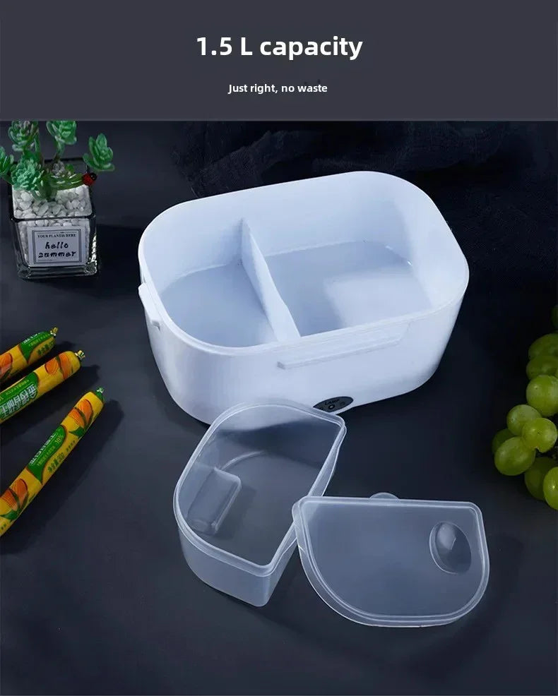 White 1.5L capacity divided lunch box with transparent lid on dark table, surrounded by snacks and grapes