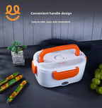 Portable electric lunch box with orange handle and clips on gray surface with grapes and snacks