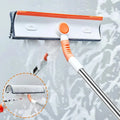 Orange and white window squeegee with microfiber cleaning pad on a soapy glass surface