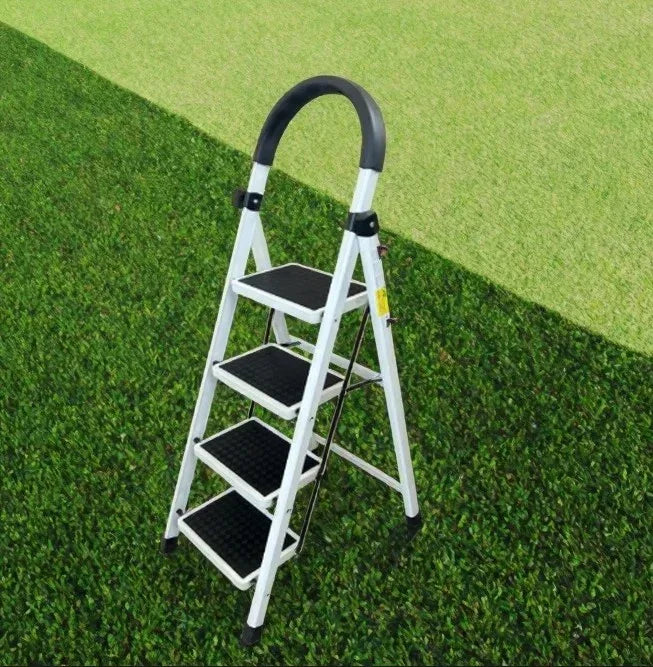 Four-step white metal ladder with black rubber treads and handle on green grass background