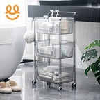 Three-tier clear plastic rolling bathroom storage cart with bottles, towels, and toiletries on gray tiled floor