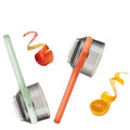 Two handheld vegetable peelers with colorful handles peeling apple and orange fruits on white background