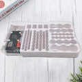 Transparent plastic organizer tray holding a battery tester and various tool bits on a white wooden surface