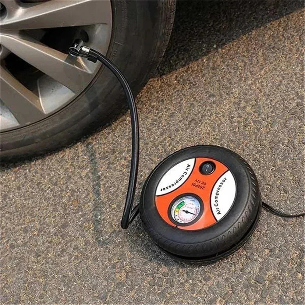 Portable air compressor inflating a car tire on asphalt with pressure gauge and power switch