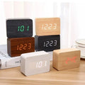 Six modern wooden digital alarm clocks with LED displays showing time and temperature on a wooden surface