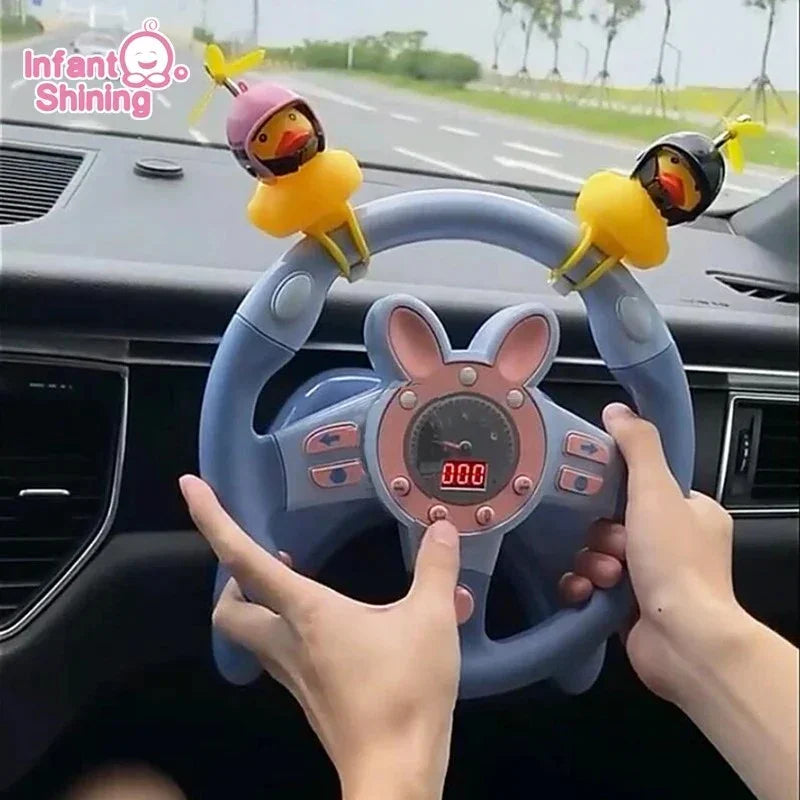 Hands holding a blue toy steering wheel with pink bunny ears and two yellow duck decorations inside a car dashboard