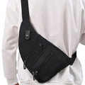 Person wearing black crossbody sling bag with multiple zipper pockets over white sweatshirt