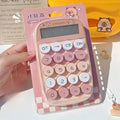 Pink capybara-themed calculator with round buttons in packaging held by hand on desk