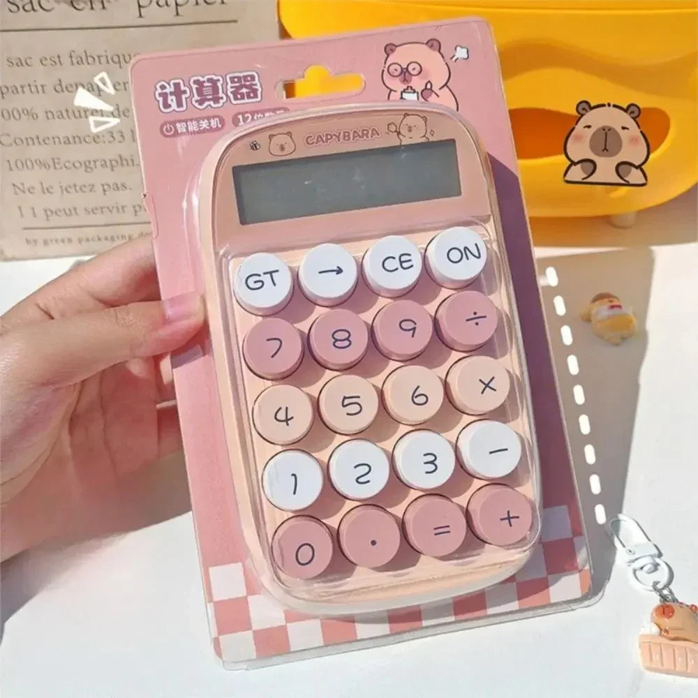 Pink capybara-themed calculator with round buttons in packaging held by hand on desk
