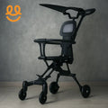Modern black stroller with ergonomic seat and canopy on tiled floor against gray wall