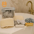 Spa essentials including bath mitts, exfoliating brushes, pumice stone, bath pouf, and headband on bathtub edge