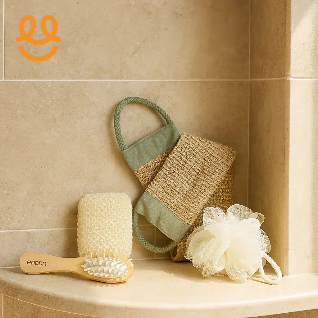 Natural bathroom essentials including bamboo brush, textured scrubber, exfoliating gloves, and bath pouf on beige tiled shelf