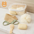 Bathroom spa essentials including natural loofah, exfoliating gloves, massaging brush, and mesh sponge on marble countertop