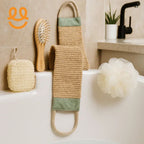 Bathroom essentials including a wooden hairbrush, woven back scrubber, white bath sponge, and exfoliating sponge on a bathtub edge