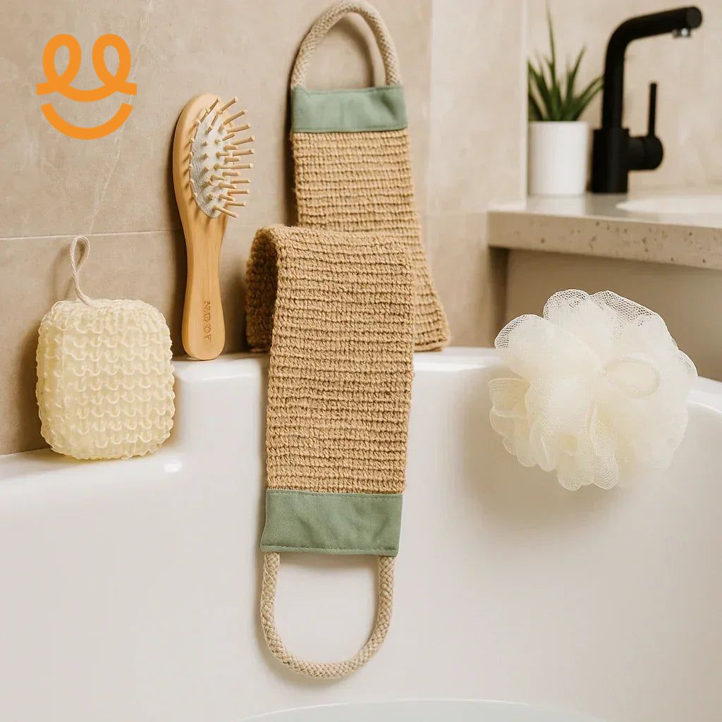 Bathroom essentials including a wooden hairbrush, woven back scrubber, white bath sponge, and exfoliating sponge on a bathtub edge