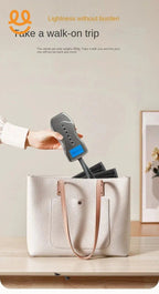 Hand placing compact black folding umbrella labeled Kong Ji PO into beige tote bag on wooden table