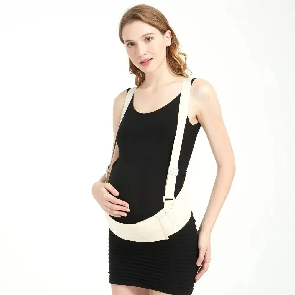 Pregnant woman wearing black dress and beige maternity support belt with straps in studio