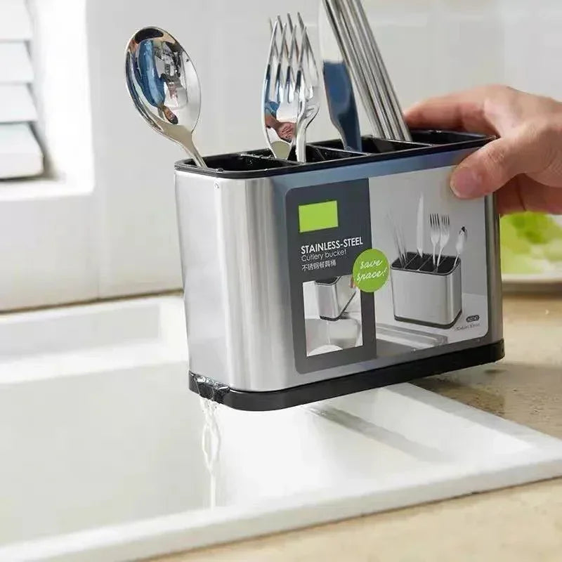 Hand holding stainless steel cutlery holder with spoons and forks draining water into kitchen sink