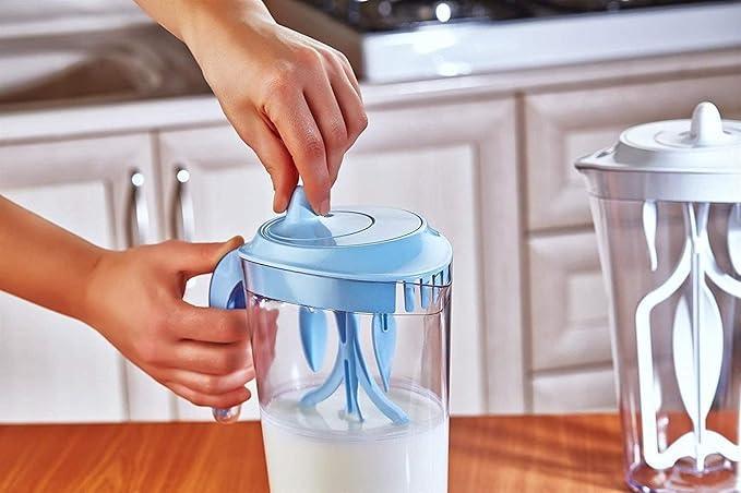 Hands holding and twisting blue lid on blender pitcher with white liquid on wooden kitchen counter