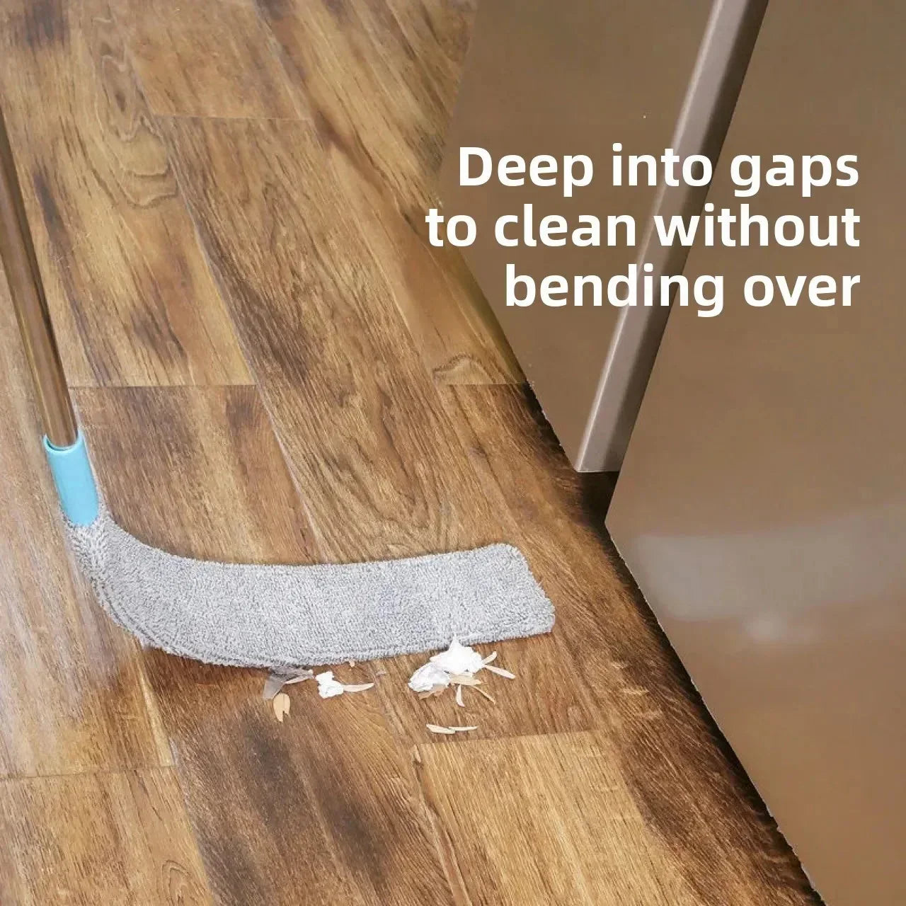 Flat mop cleaning dust and debris from wooden floor gap near kitchen cabinets