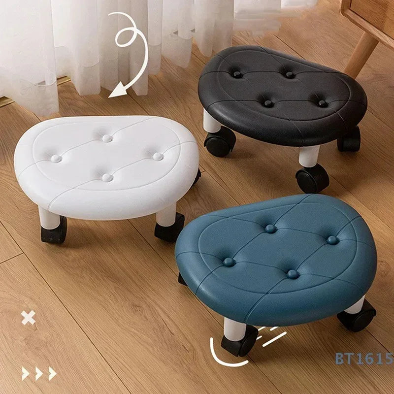 Three leather padded rolling footstools in white, black, and blue on wooden floor