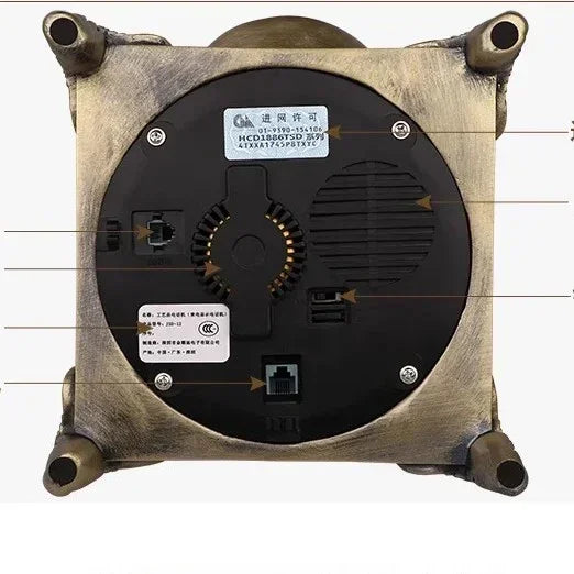 Bottom view of a metallic, square-shaped electronic device with ports, labels, and four stand feet