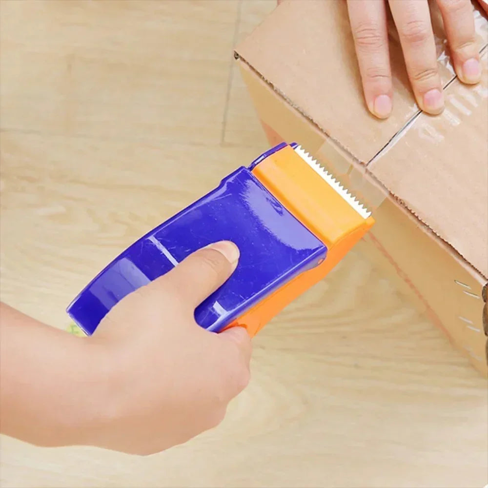 Hand using a purple and orange tape dispenser to seal a cardboard box on a wooden floor
