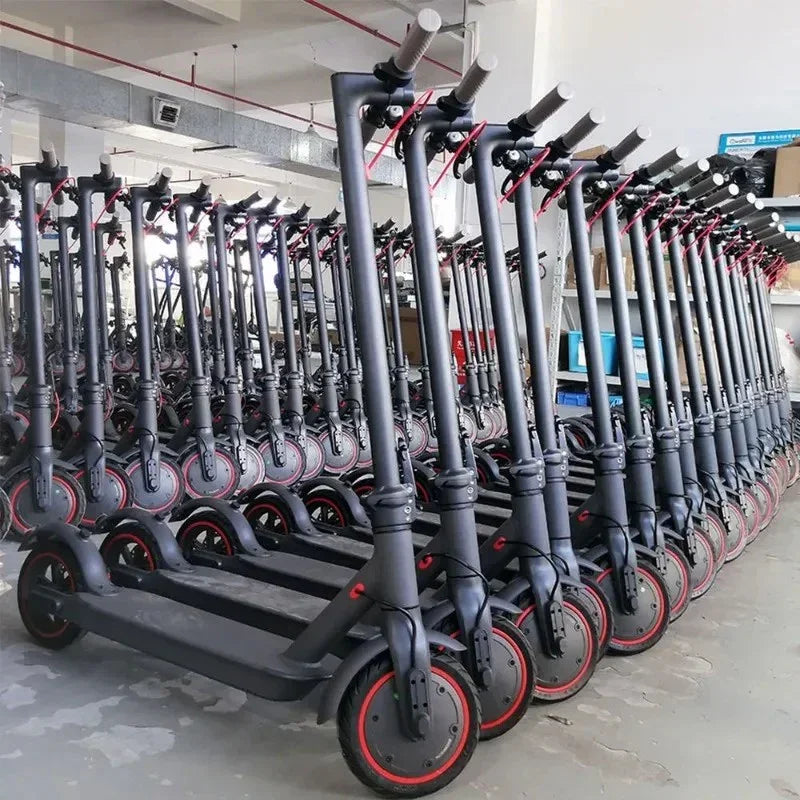 Rows of black electric scooters with red accents lined up indoors in a warehouse setting
