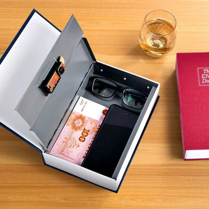Hidden security safe disguised as a book, containing cash, glasses, and a smartphone on a wooden table with a glass of whiskey and a red dictionary nearby