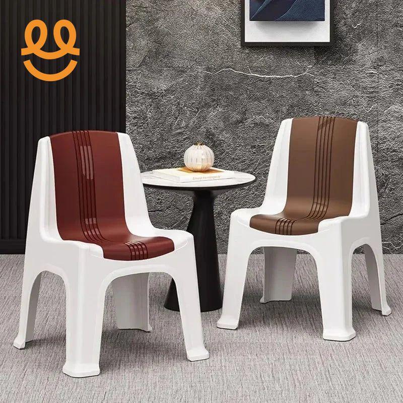 Two white plastic chairs with brown and maroon seat stripes beside a round black and white side table with decor