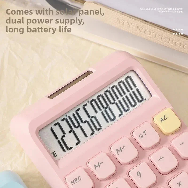 Pink solar-powered calculator with large display on beige surface, featuring dual power supply and long battery life