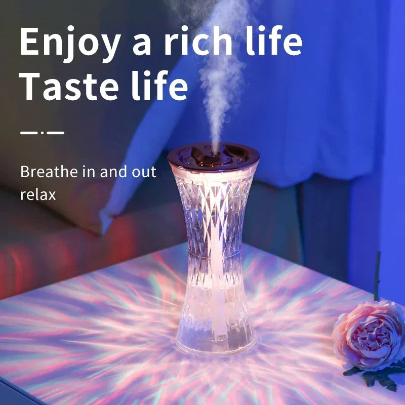 Crystal-patterned essential oil diffuser emitting mist on illuminated table with pink flower in cozy room