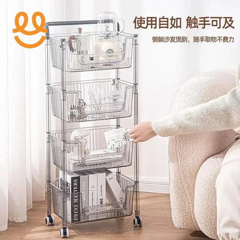 Clear plastic rolling storage cart with four baskets holding books, ceramics, and kitchenware