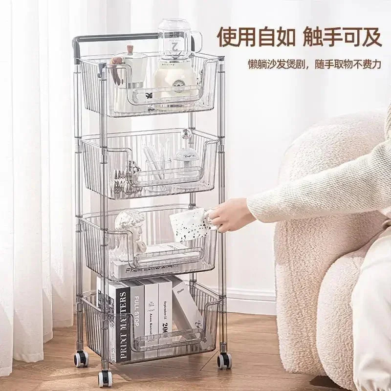 Clear plastic rolling storage cart with four baskets holding books, ceramics, and kitchenware