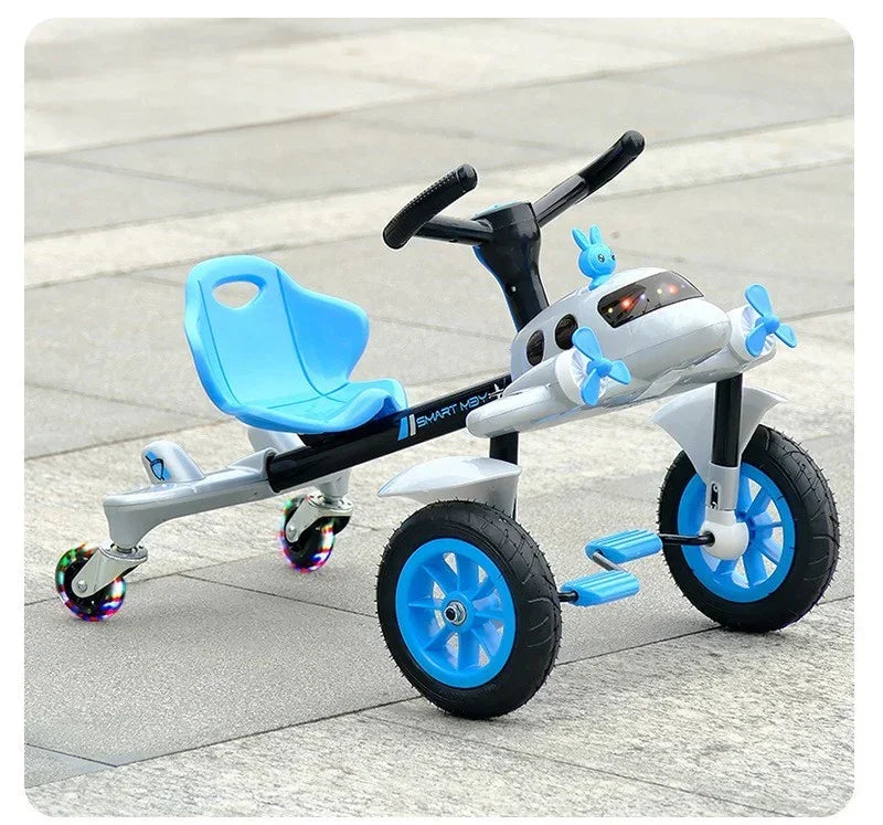Blue and white kids tricycle with airplane design and light-up rear caster wheels on pavement