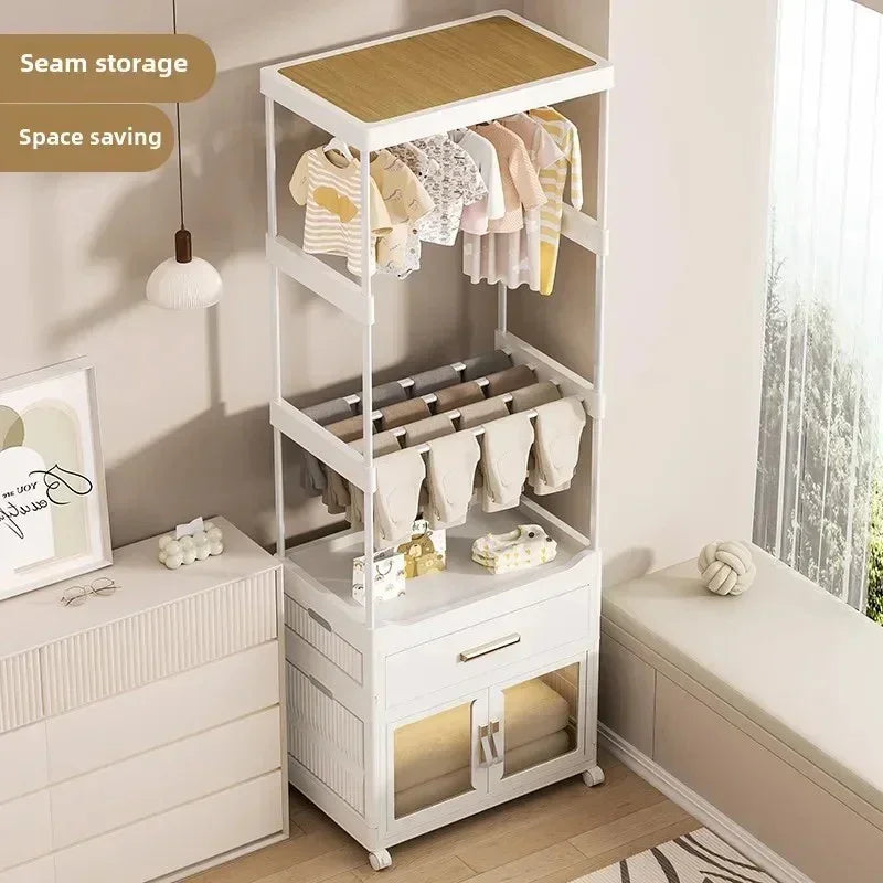 Modern white baby clothes storage rack with hanging rods, shelves, and cabinet in nursery room