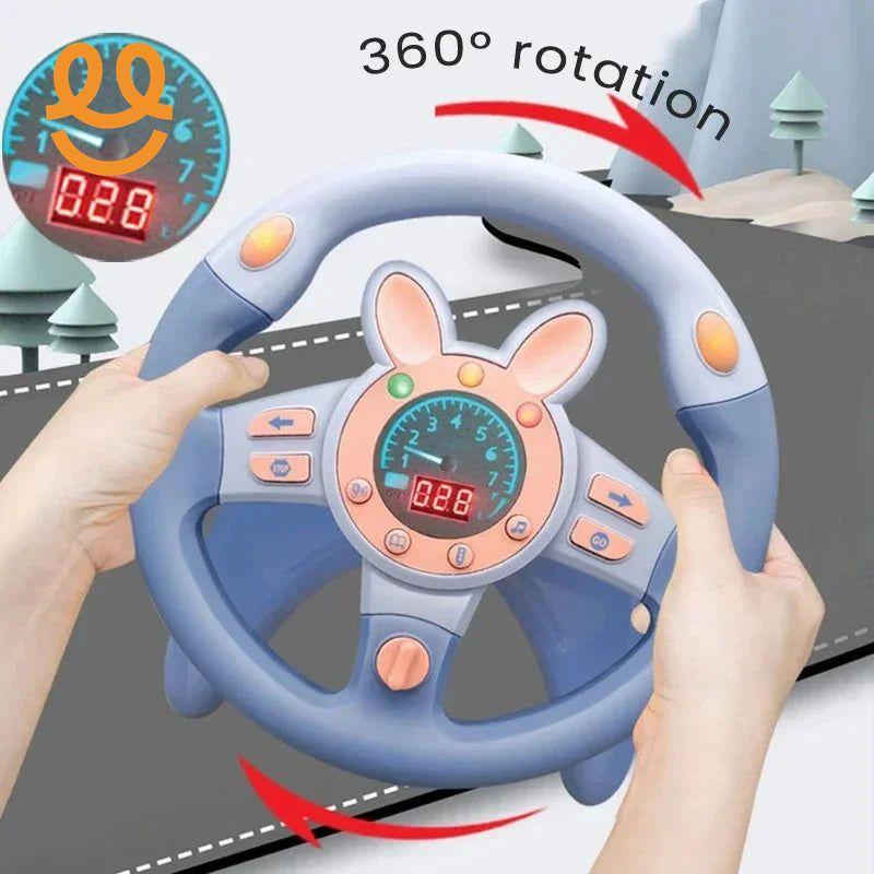 Hands holding a blue and pink kids toy steering wheel with 360° rotation feature and dashboard display