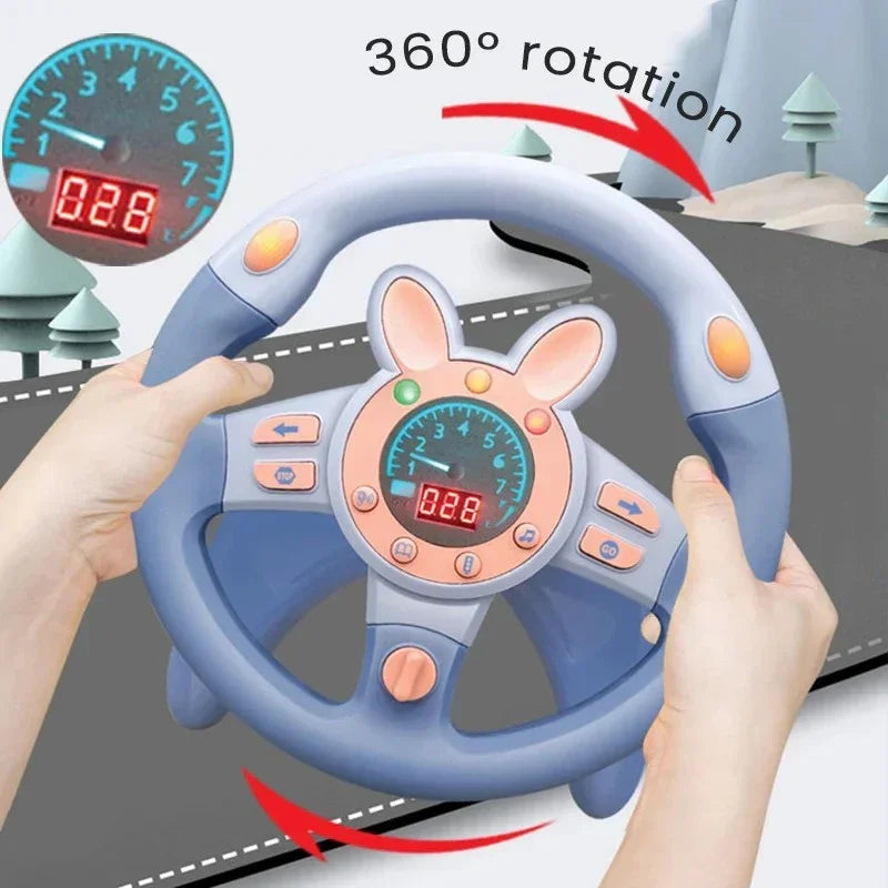 Hands holding a blue and pink kids toy steering wheel with 360° rotation feature and dashboard display
