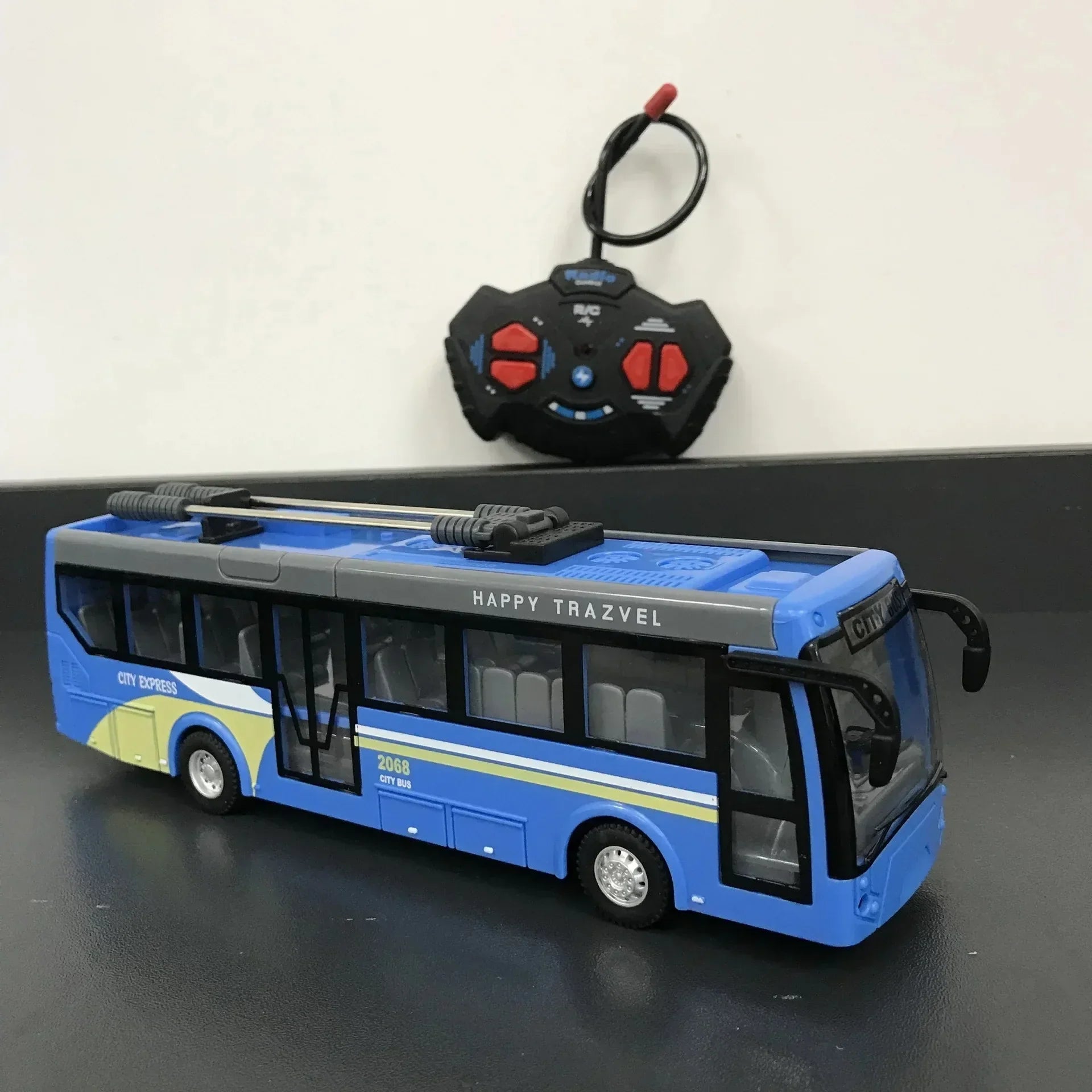 Blue and yellow remote control toy city bus with black controller on black surface