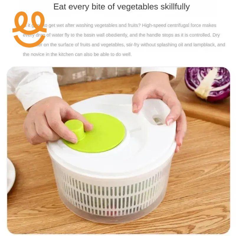 Hands using a white and green salad spinner on wooden table with purple cabbage in background