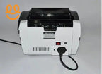 Back view of a white and black bill counter machine with power switch and plug connected