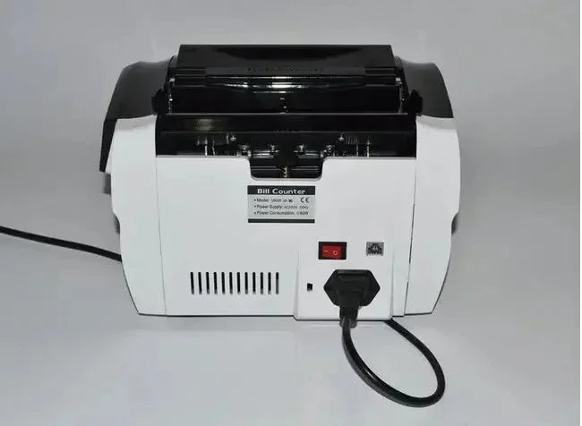 Back view of a white and black bill counter machine with power switch and plug connected