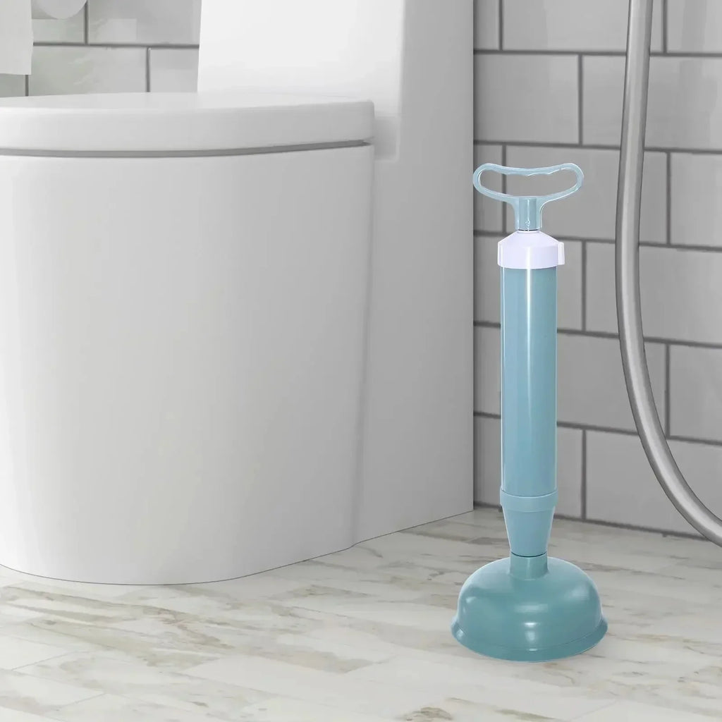 Blue handheld toilet plunger with pump handle next to white toilet in modern bathroom