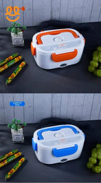 Two electric lunch boxes in orange and sapphire blue with food items and a small plant on dark surface