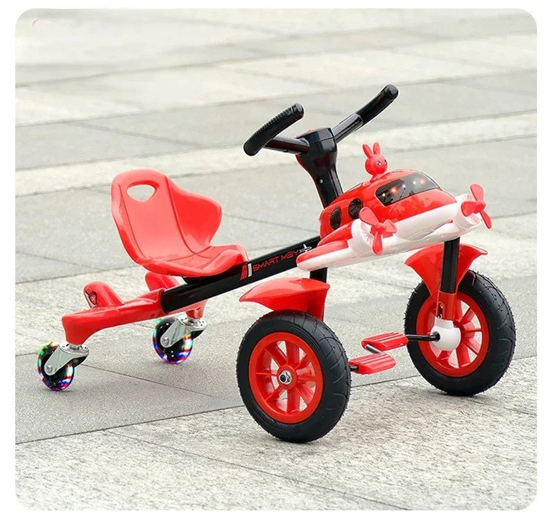 Red children's tricycle with airplane design, front propellers, LED wheel lights, and rear swivel wheels on pavement