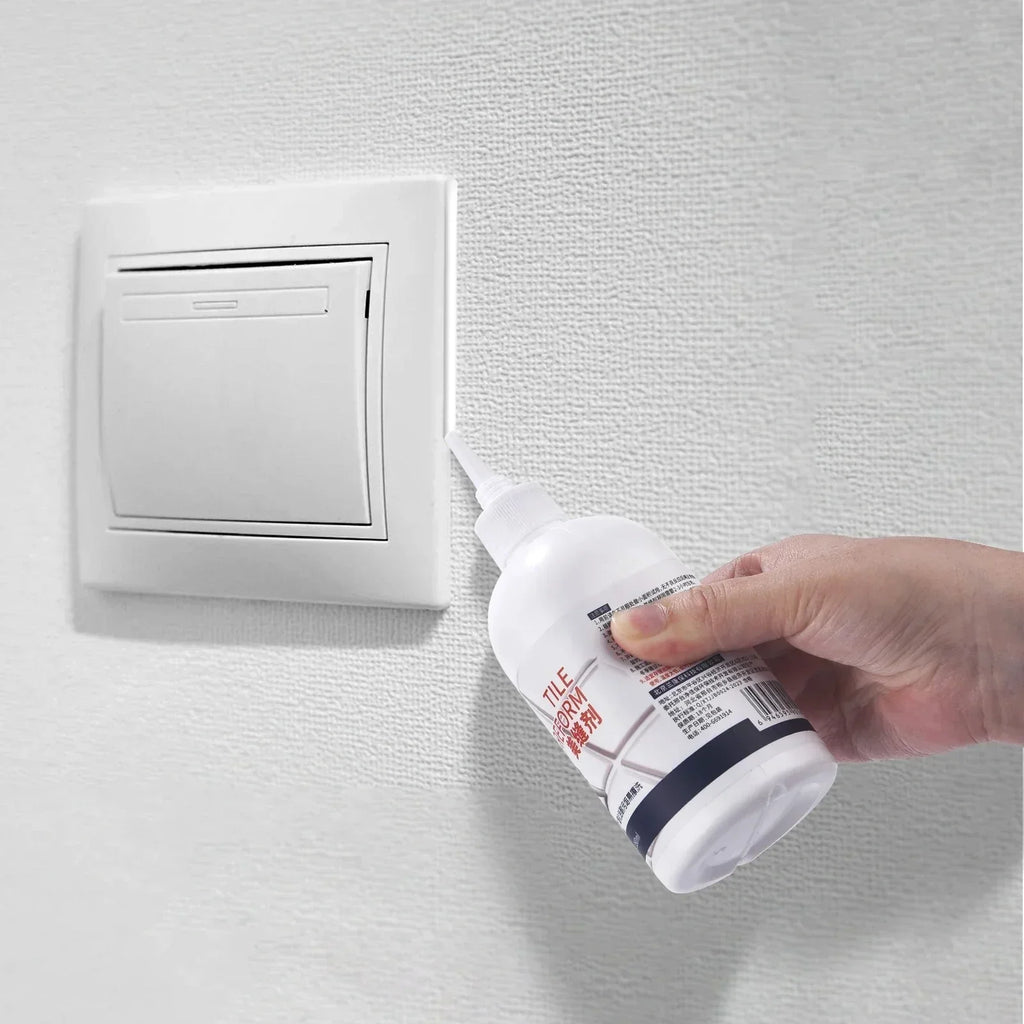 Hand holding white bottle applying tile reform grout cleaner near wall light switch on textured wall