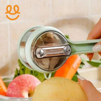 Hand using a handheld rotary vegetable peeler to peel a potato with carrots and an apple in the background