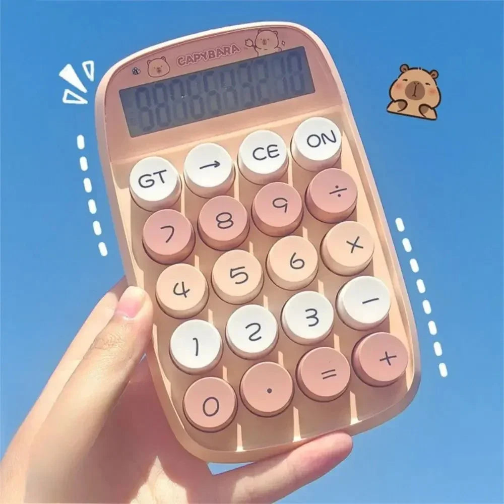Hand holding a pink and beige capybara-themed calculator against a clear blue sky